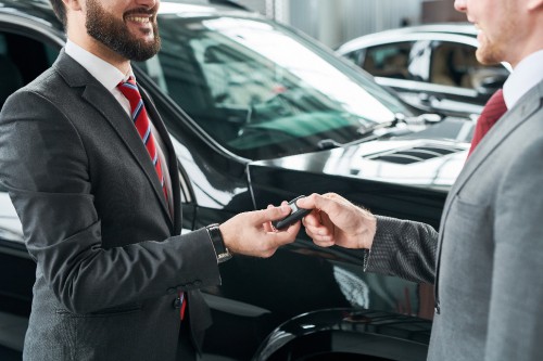 Car salesman handing car keys to man in showroom