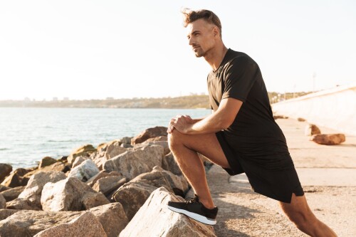 middleagedmanstretchingbeforerunningbythebeach-1920w.jpg