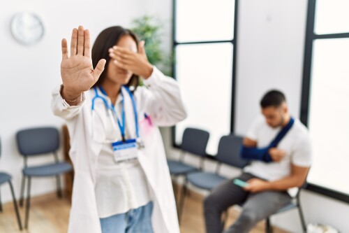 young-asian-doctor-woman-waiting-room-with-man-with-broken-arm-covering-eyes-with-hands-doing-stop-gesture-with-sad-fear-expression-embarrassed-negative-concept.jpg